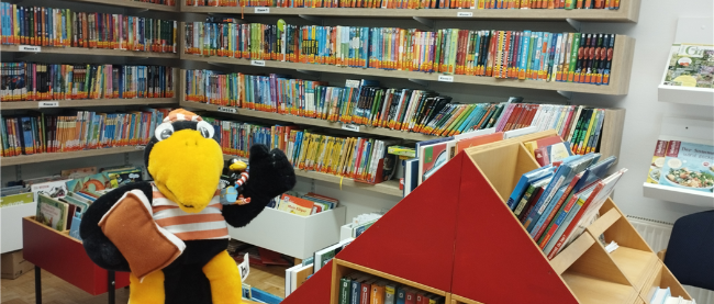 Rabe Fridolin vor Bücherregal