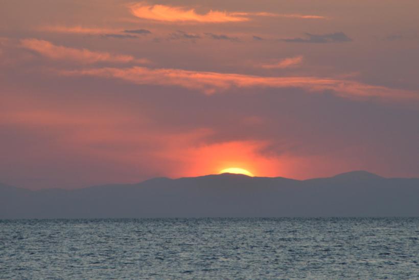 Sonne kurz vor dem Untergang hinter eine Wolke über dem Meer am Horizont