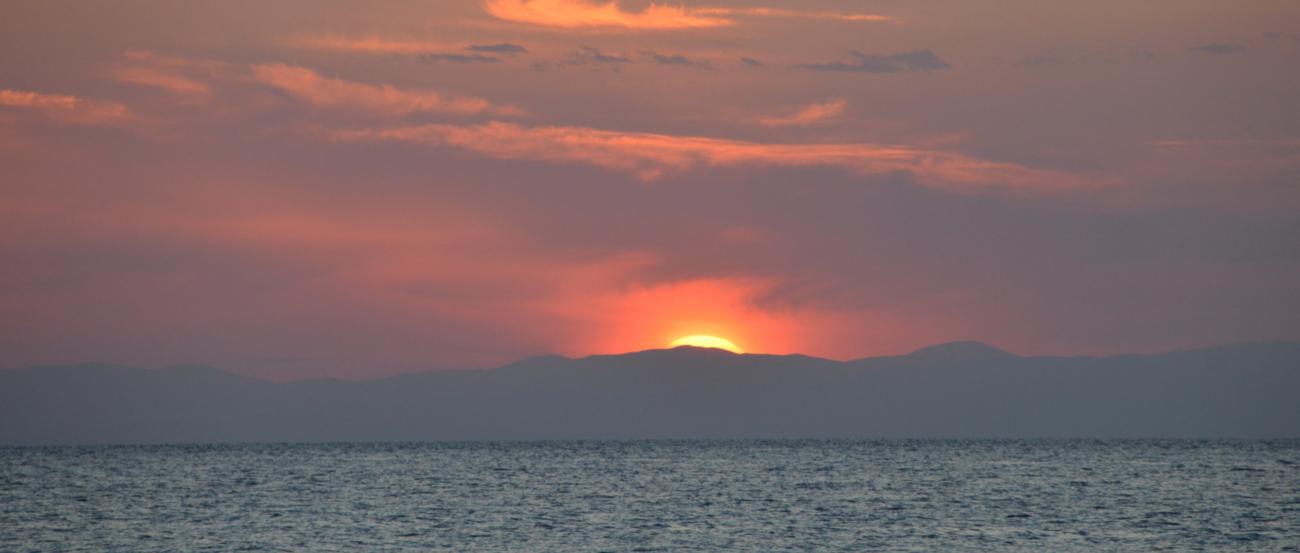 (c) Wolfgang Spanier Sonne kurz vor dem Untergang hinter eine Wolke über dem Meer am Horizont