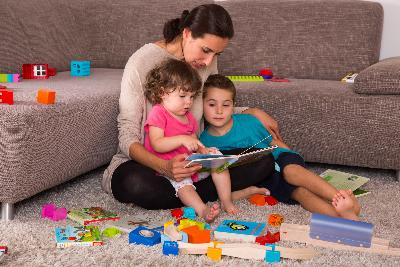 (c) Müttergenesungswerk Mutter mit Kindern bei der Buchbetrachtung und beim Spielen