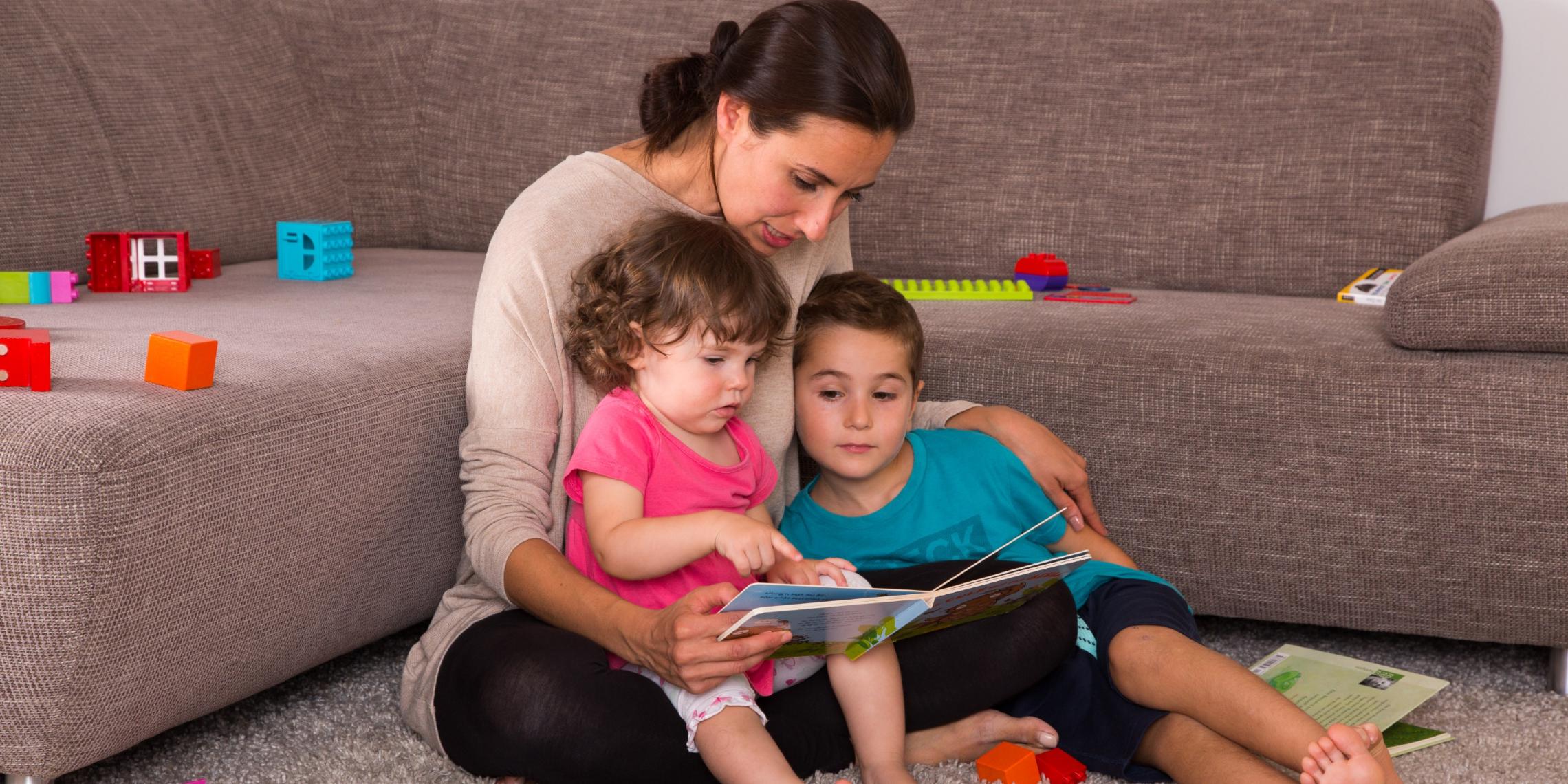 Mutter mit Kindern bei der Buchbetrachtung und beim Spielen